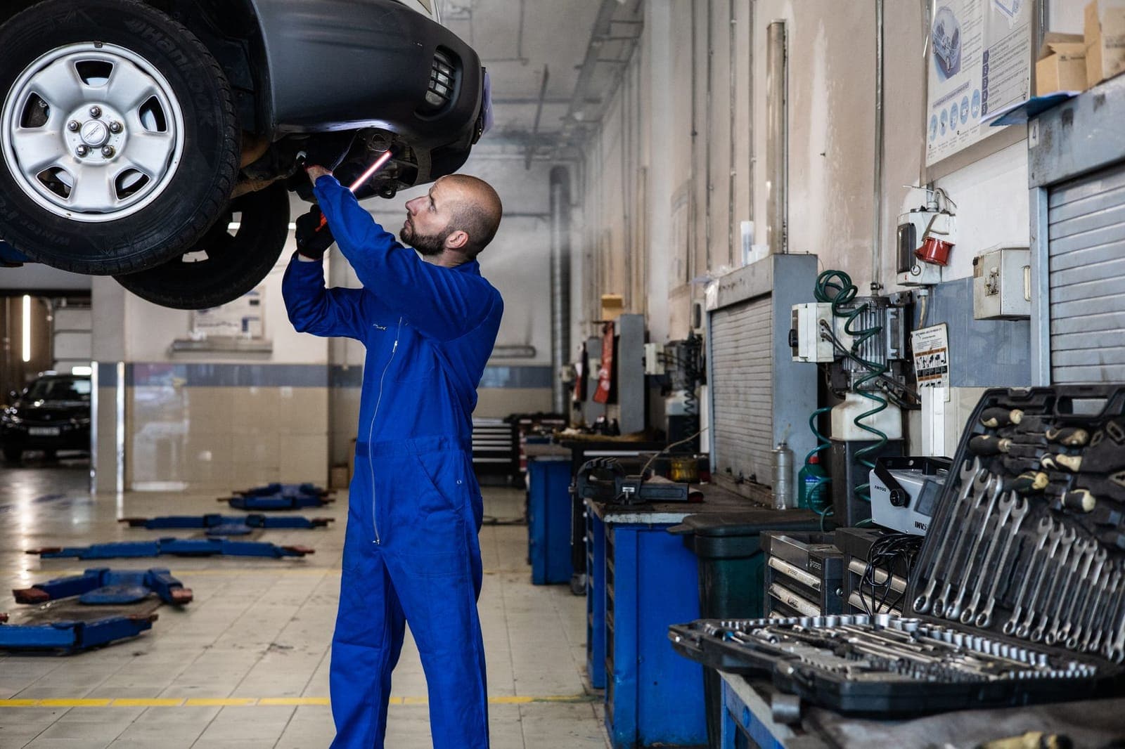 Monteur in blauwe overall tilt een wiel op in de werkplaats